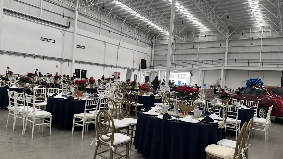 Evento en nave industrial con mesas de mantel negro y sillas Tiffany