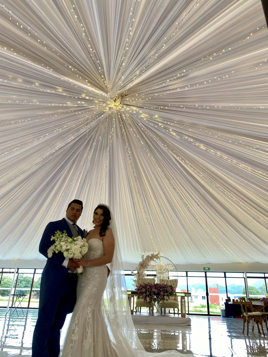 Pareja de novios bajo un techo de telas y luces