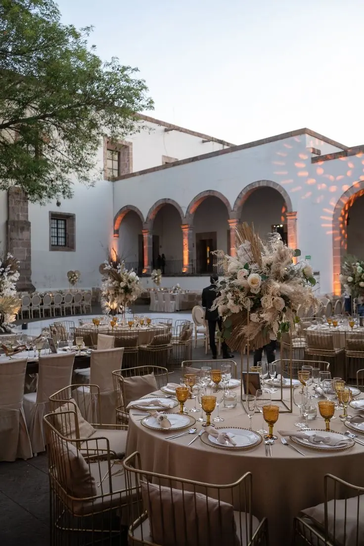 Banquete en patio de hacienda con mesas redondas y flores