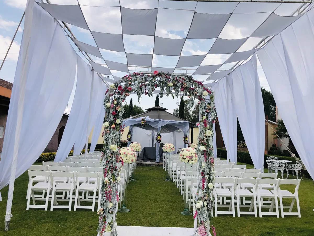 Ceremonia con arco floral bajo telas blancas