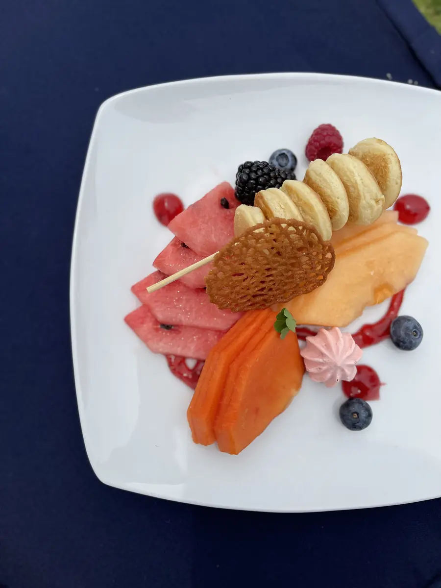 Postre de frutas emplatado con merengue y teja